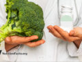 doctor holding broccoli in one hand and pill bottle in the other