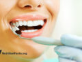 Gloved hand holding dental mirror to inspect teeth