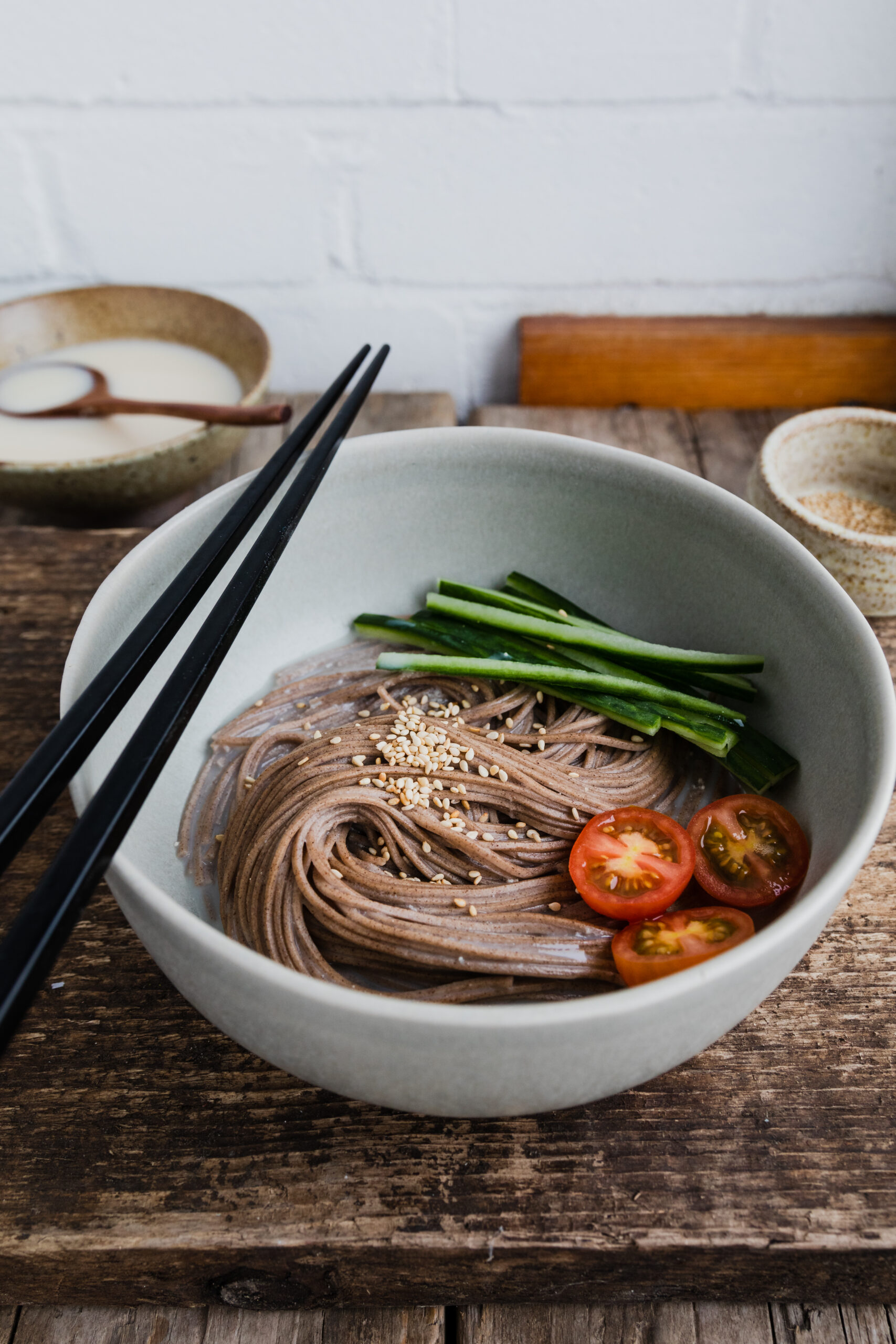 bowl of soba noodles with soymilk broth, sliced cucumber, and halved cherry tomatoes